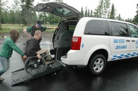 Photo of wheelchair user being assisted into an accessible van with Alaska Cab.